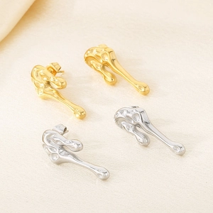 Detail view of gold and silver irregular fluid lava style earrings on beige fabric