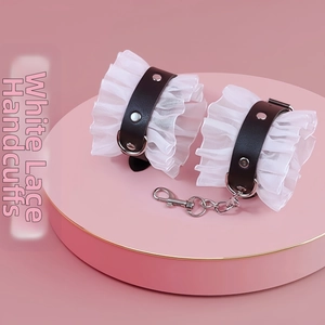Detailed close-up of white lace handcuffs with black leather straps and metal chains