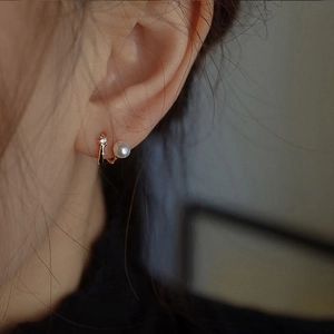 Detail of French vintage pearl earrings with gold circle and zircon stud on ear