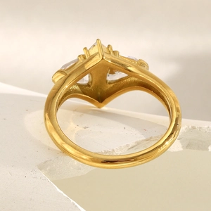 Macro shot of 18K gold butterfly ring with cubic zirconia on a white textured base