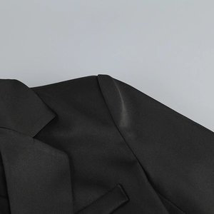 Détail du revers d'un blazer noir à col en V montrant la texture du tissu en sergé premium
