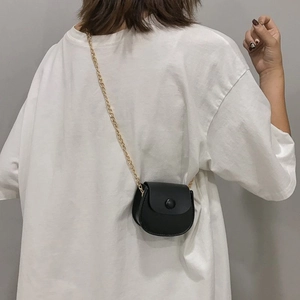 Mini sac à main selle noir avec bandoulière chaîne dorée porté par un mannequin