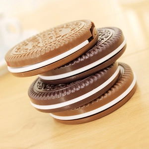 Chocolate cookie shaped portable folding makeup mirrors in black and tan stacked on wood