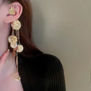 Orecchino a polsino dorato con nappa di paillettes rotonde indossato da una modella