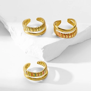 Detail of 18K gold plated textured rings with colorful enamel stripes on a stone base