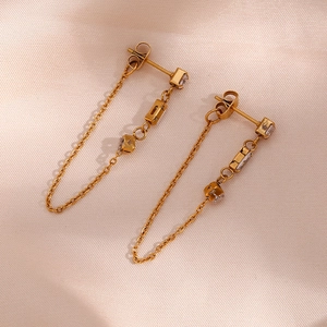 Detailed macro shot of gold chain earrings with sparkling zircon on champagne satin