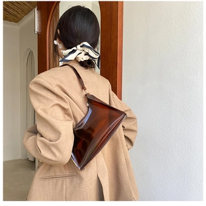 Detailed back view of a transparent brown PVC baguette shoulder bag worn by a model