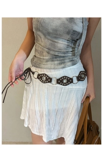 Detail of dark brown leather geometric belt with silver metal rivets on white dress