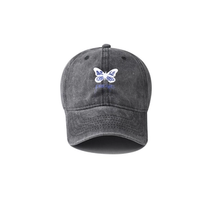 Détail de la broderie papillon et du texte bleu Dreams sur casquette en coton délavé