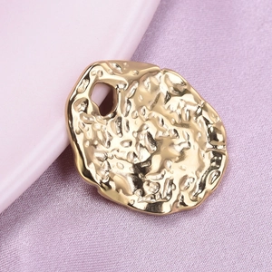 Macro shot of irregular golden hammer textured metal pendant with 304 stainless steel detail