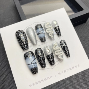 Macro detail of black snake-themed long coffin nails with silver accents and 3D charms