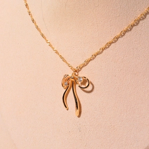 Detail of gold bow necklace with sparkling zircon pendant on model neck