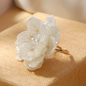 Macro shot of a large white woven flower ring with pearl luster and golden center