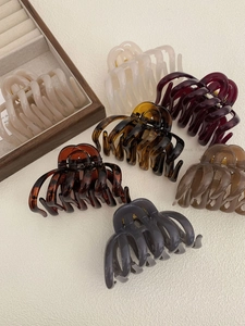 Top view of large pumpkin hair claws in various glossy colors on a beige background