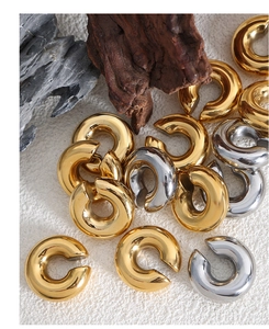 Macro shot of minimalist C-shape geometric ear clips in gold and silver mirror finish