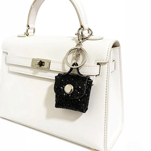 Close-up of black glitter mini pouch keychain with silver clasp on a white handbag