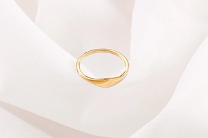 Elegant gold-plated wave design ring displayed on a luxurious white pleated silk background