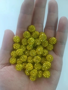 Close-up of sparkling golden and yellow-green rhinestone disco beads held in hand