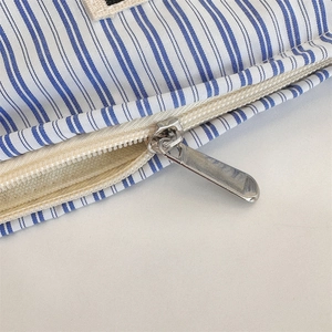 Detailed close-up of the smooth silver metal zipper on a blue striped toiletry bag