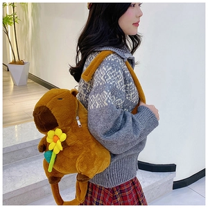 Detail of Capybara plush backpack with yellow flower shown on a model in bright room
