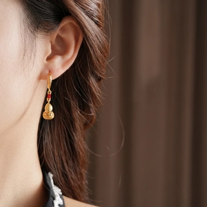 Gold plated calabash earrings on model with matte finish and hollowed detail