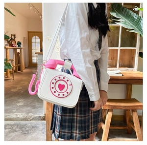 Close-up detail of a creative vintage telephone shaped crossbody bag in pink and white.