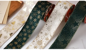 Close-up of dark green and cream Christmas ribbons with gold foil snowflakes and trees