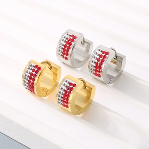 Detailed close-up of gold and silver ear hoops with red rhinestones on a white podium