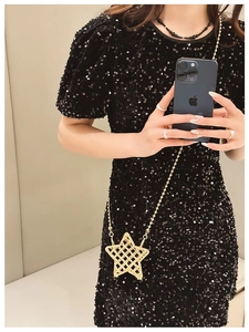Mirror selfie showing a glossy gold star-shaped metal bag with a fine chain strap