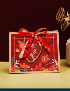 Chinese wedding gift bag with floral patterns, gold rope, and red and white ribbon bow