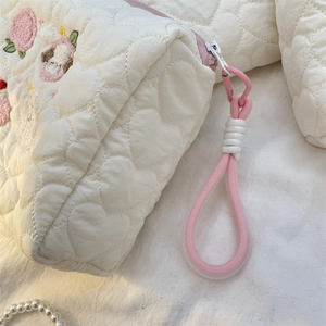 Detail of cream quilted makeup bag featuring heart stitching and peach embroidery