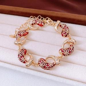 Macro shot of gold bracelet with red enamel and rhinestones in a velvet jewelry box