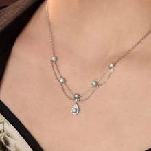 Detail of s925 silver layered necklace with teal beads and water drop pendant on a model