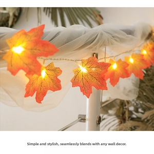 Detail view of glowing LED maple leaf lights with realistic orange texture and warm glow