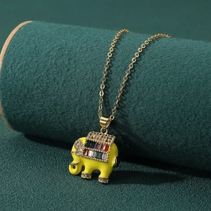 Cute yellow elephant pendant necklace with rainbow zircons on a dark green display