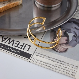 Detail of 18K gold-plated double-layer open bangle with minimalist hammered texture