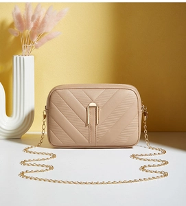 Detail of beige V-quilted faux leather bag with elegant gold metal chain strap and hardware
