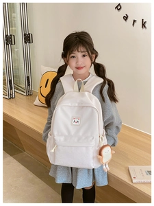 Pink school bag for girls with cute cat patch and bread plush charm in a bright setting