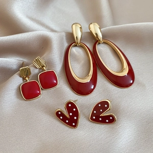 Close-up of red enamel and pearl earrings set displayed on champagne silk fabric