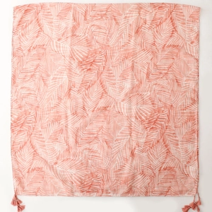 Close-up of coral pink palm leaf print scarf featuring decorative corner tassels on fabric