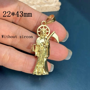 Detail of 22x43mm gold Santa Muerte pendant held in hand for size visualization