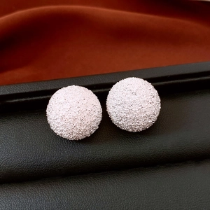 Macro shot of silver circular stud earrings with a textured matte finish on leather