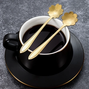 Goldene Kirschblütenlöffel aus Edelstahl auf einer dunklen Keramiktasse