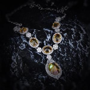 Close-up of yellow oval gemstone necklace with white diamond halo on a black rock