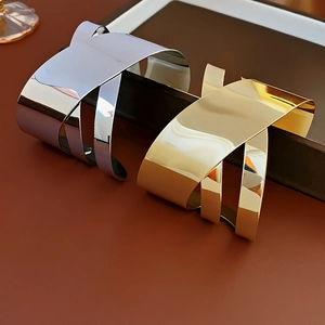 Detailed close-up of wide irregular crossover metal bangles in gold and silver finish