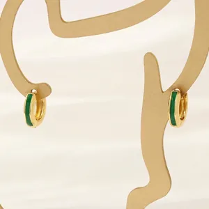 Close-up of 18K gold hoop earrings with green enamel and brushed metal finish