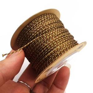 Close-up of 1mm golden brown metallic braided cord wrapped on a cardboard spool