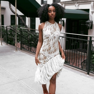 Détail d'une robe sans manches en dentelle blanche avec ourlet volanté asymétrique et motifs