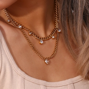 Detail of gold double-layer necklace featuring polished chains and white cubic zirconia