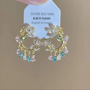 Makro-Detail von goldenen Blumenohrringen mit bunten Kristallen und 925er Silberstecker